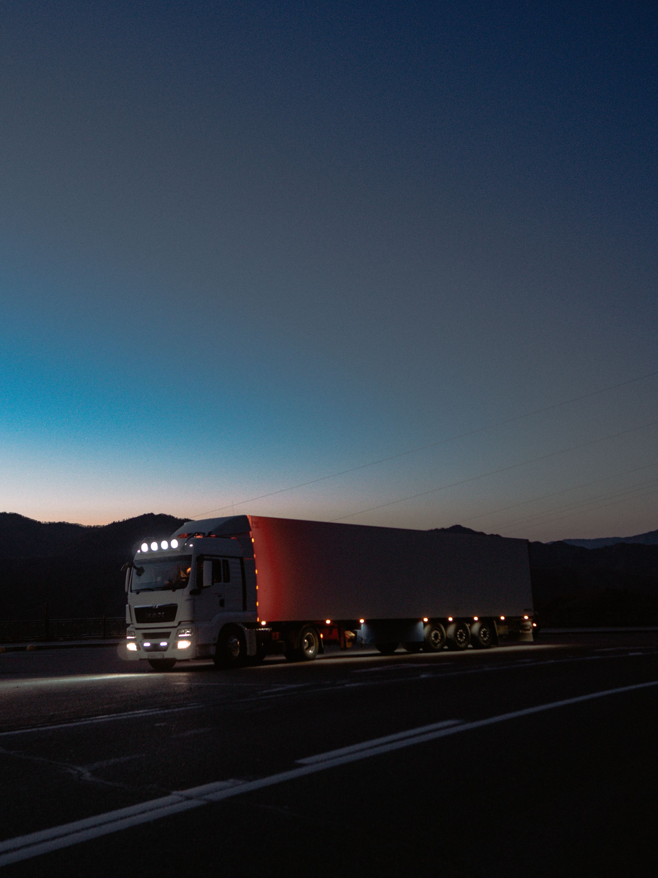 A freight truck travelling along a highway at dusk